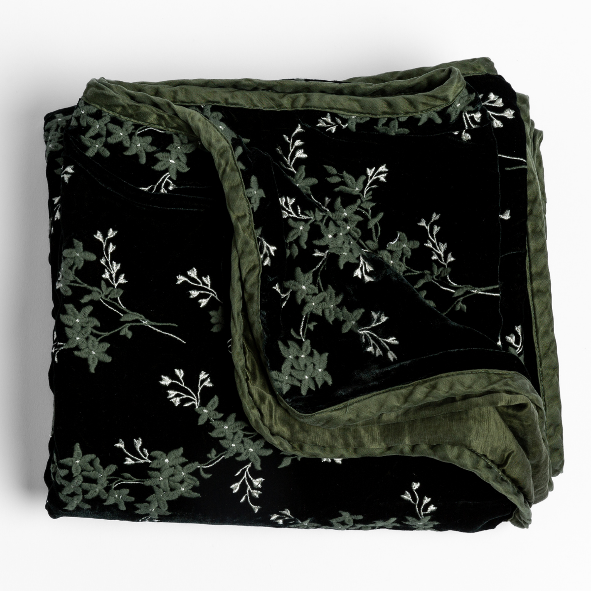 Juniper velvet throw blanket folded, showing black face with sage floral embroidery and olive reverse.