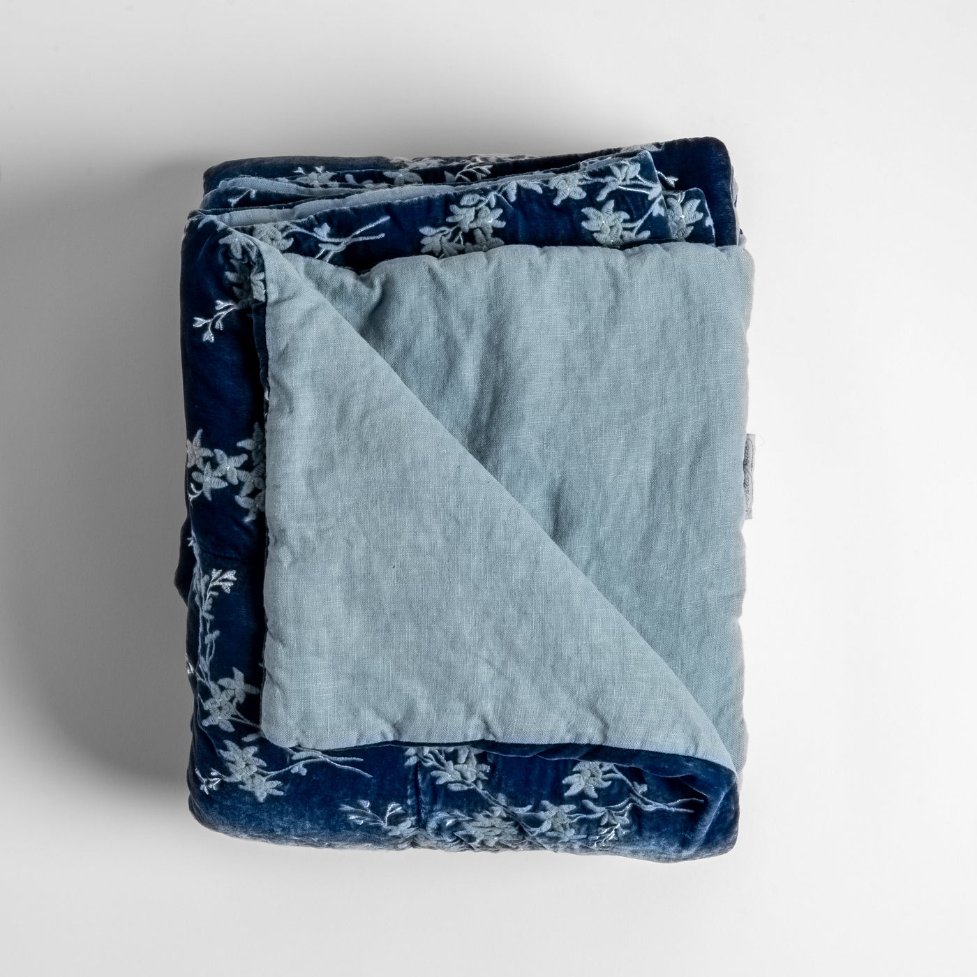 Folded Bella Notte Lynette blanket, Tahoe Blue floral velvet exterior with pale linen reverse.