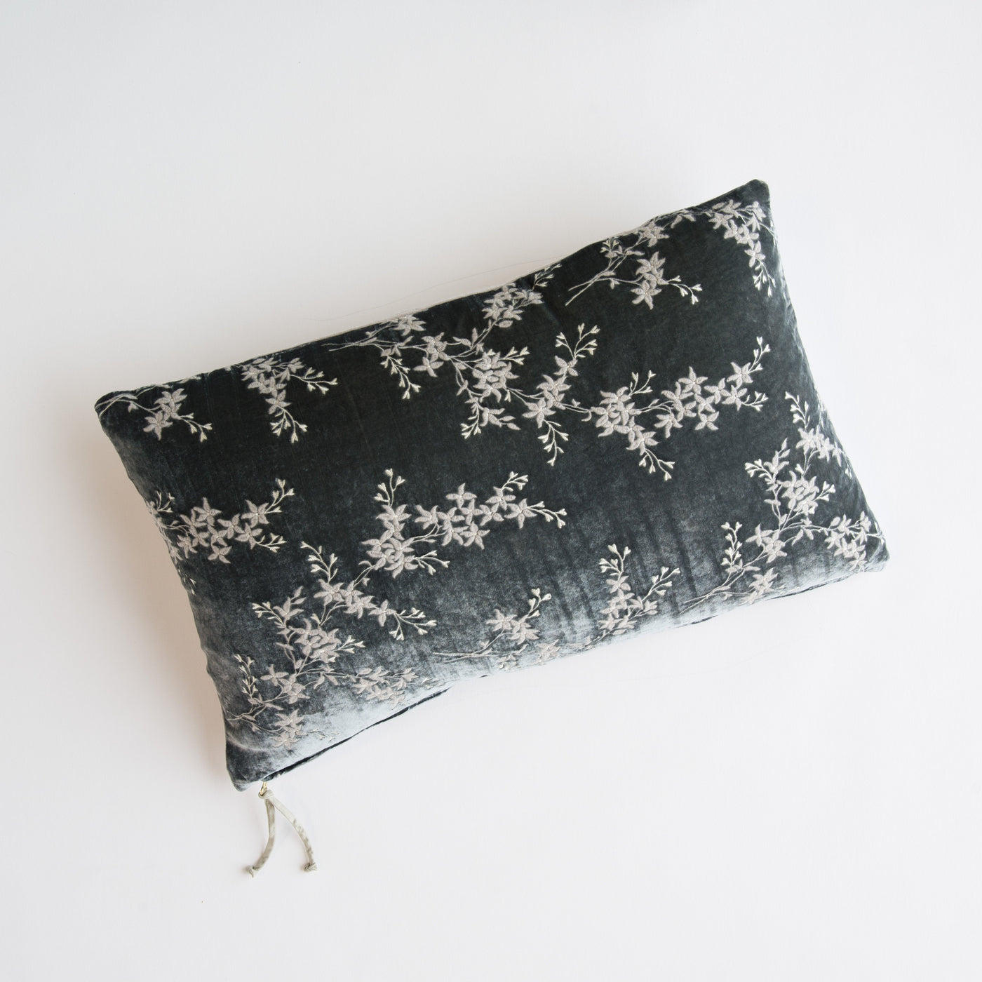 Fog velvet lumbar pillow with scattered ivory floral embroidery, viewed from above on white surface.