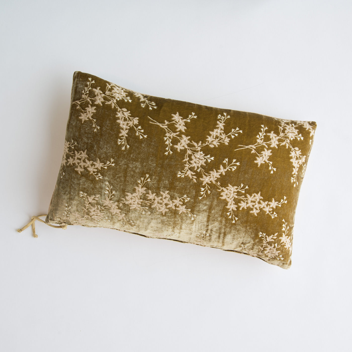 Honeycomb velvet lumbar pillow with cream floral branch embroidery and tassel detail.