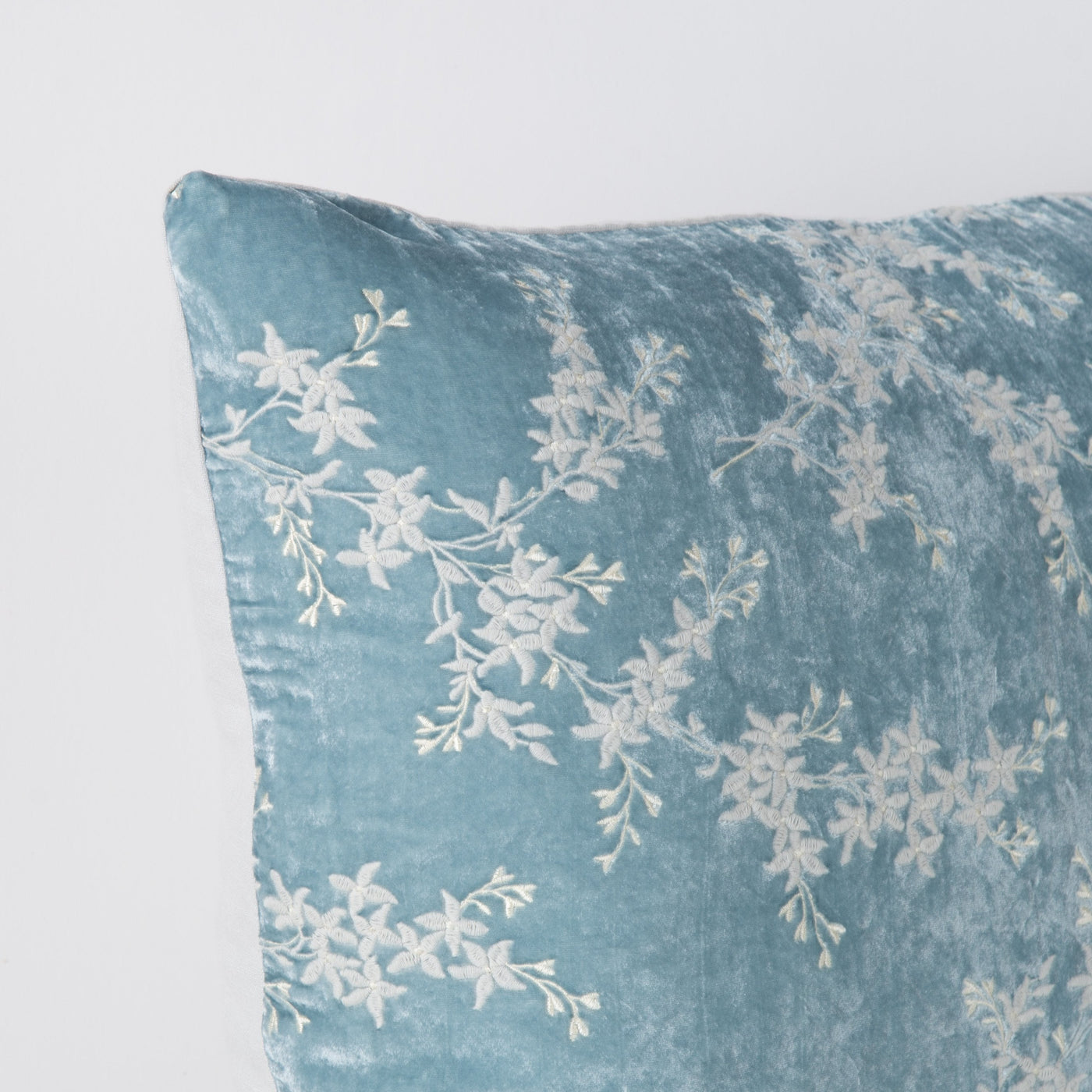 Close-up of Cloud velvet sham corner with ivory floral embroidery on crushed texture.