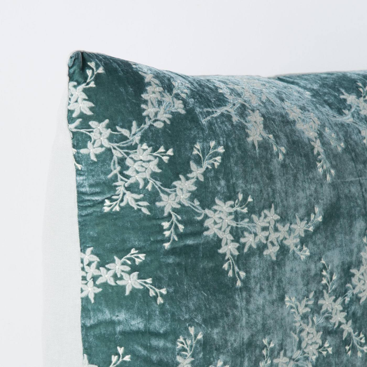 Corner detail of Eucalyptus velvet sham with white floral embroidery and knife edge trim.