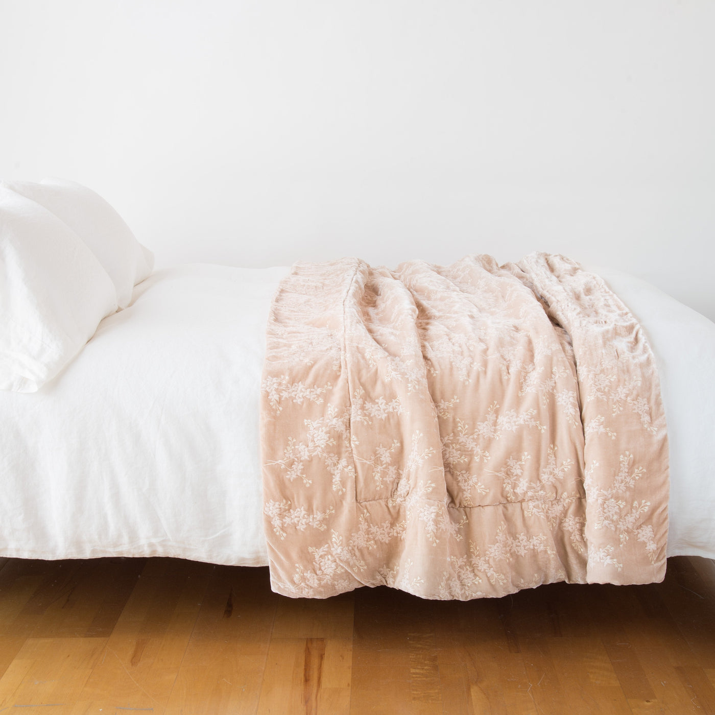 Lynette blanket in Pearl draped across foot of bed, floral jacquard texture visible.