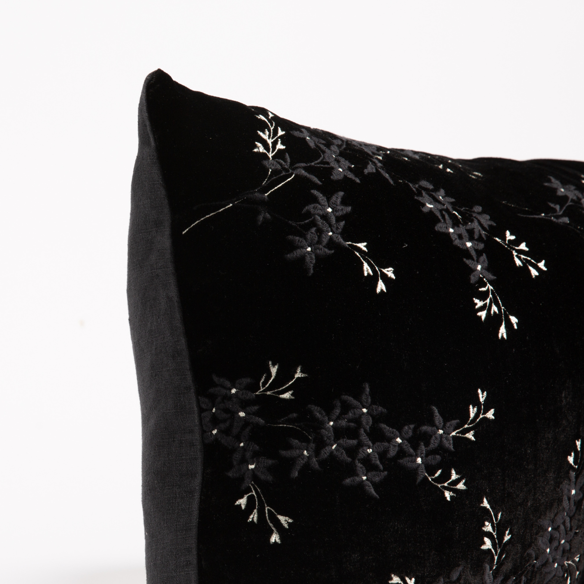 Corner detail of Corvino velvet sham with tonal floral embroidery and pearl accent stitching.