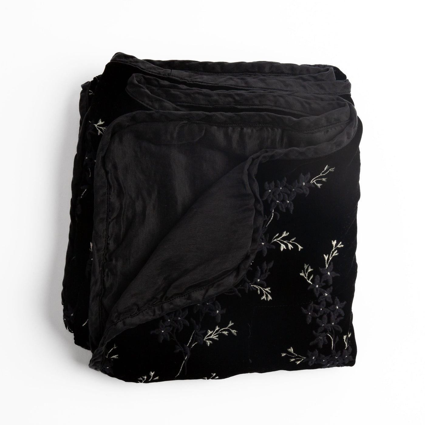 Corvino velvet throw folded to show floral embroidery detail and contrast satin lining edge.