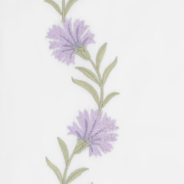 Close-up of lavender cornflower embroidery with sage green stems on ivory linen.