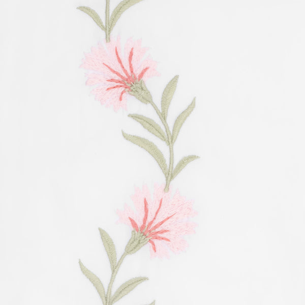 Close-up of pink floral embroidery with sage green stems on white cotton.