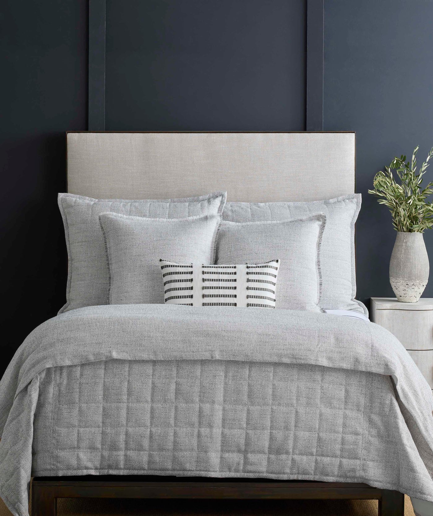 Ann Gish Macau duvet cover in silver-grey on a styled bed against a navy wall.