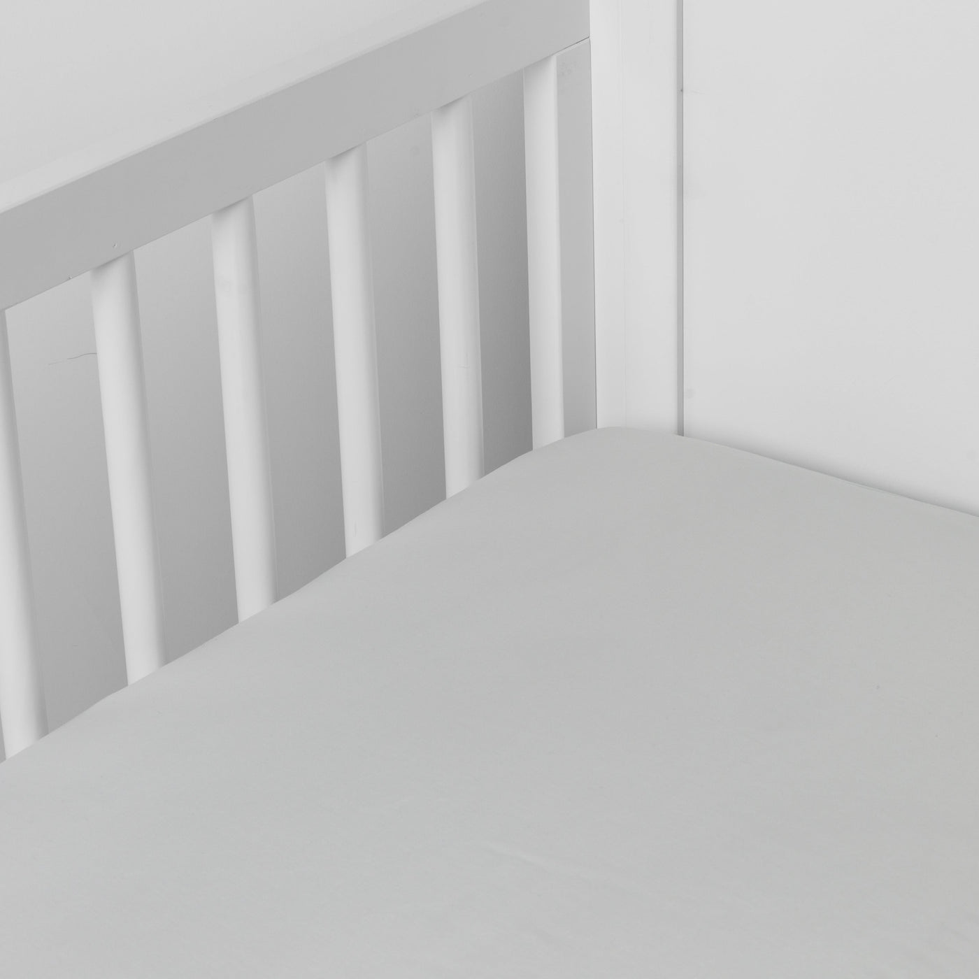 Fitted Cloud crib sheet on white crib slats, smooth Madera Luxe fabric close-up.