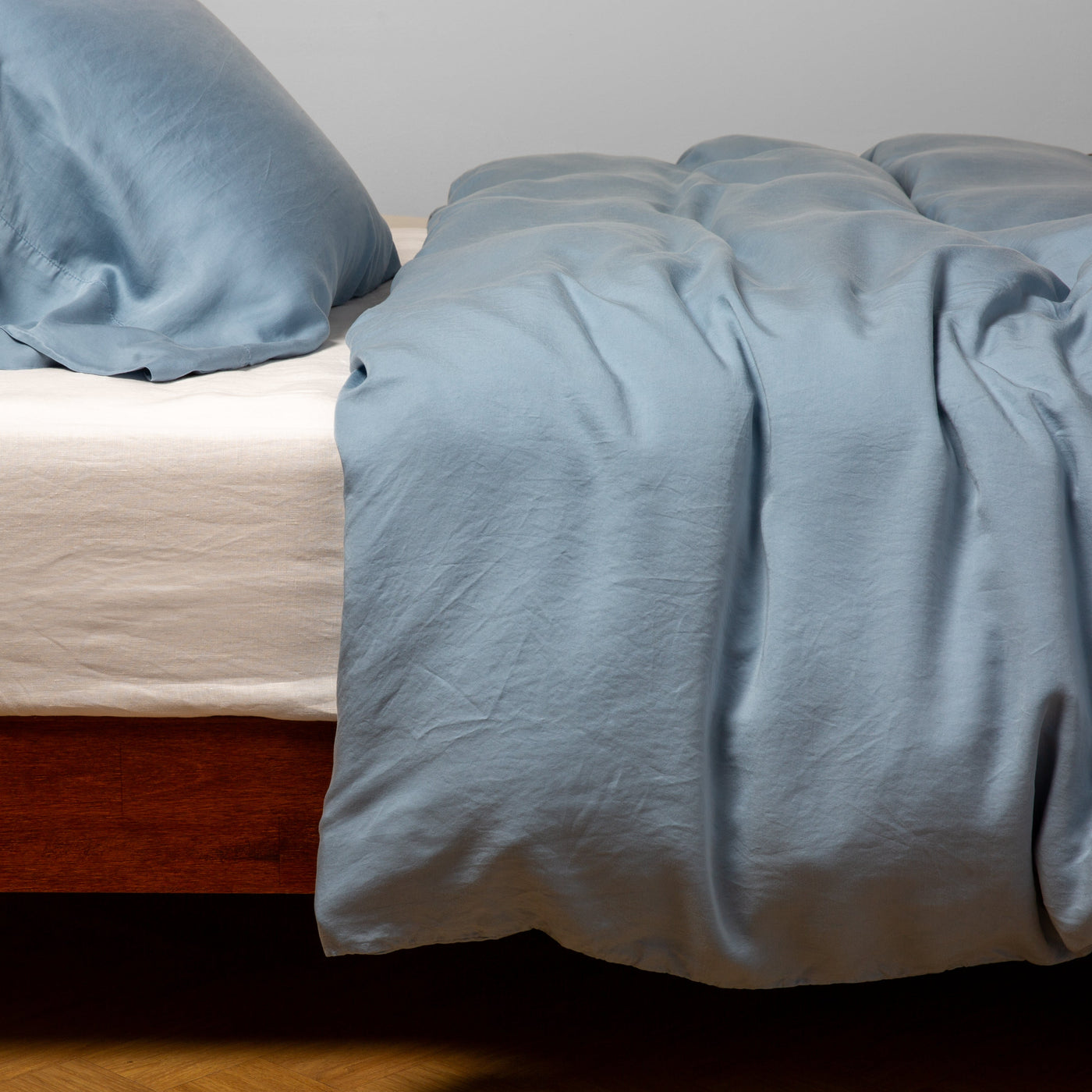 Bella Notte Madera Luxe duvet cover in Tahoe Blue, draped over bed with matching pillowcase.