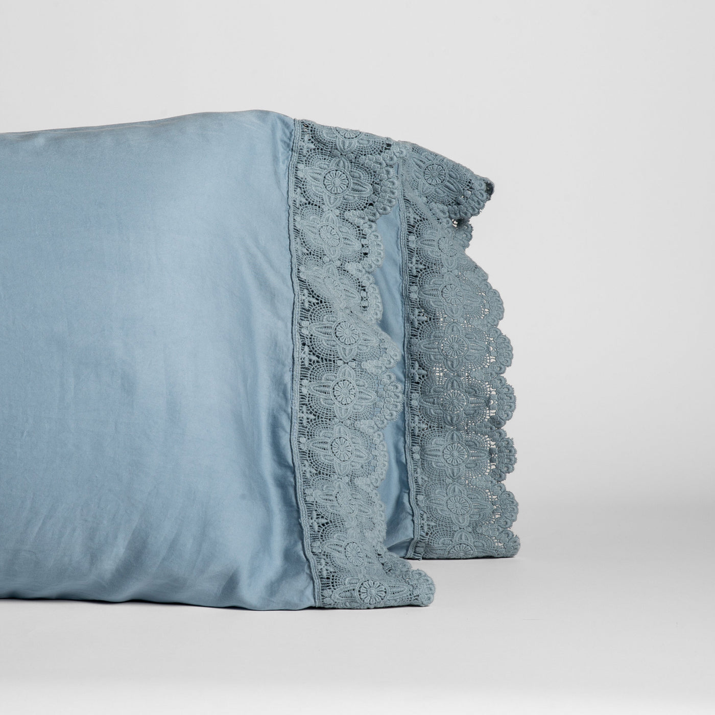 Lace trim detail on Tahoe Blue Madera Luxe pillowcase edge, pair stacked.