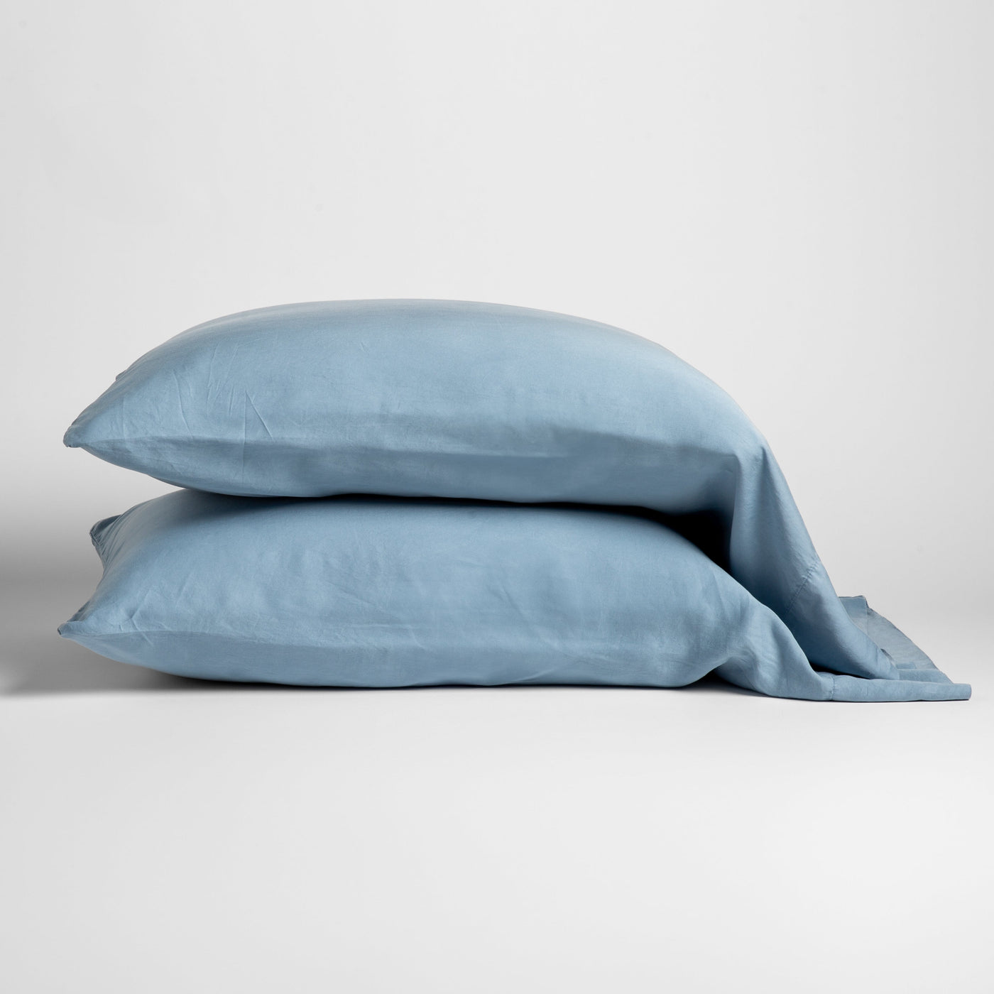 Two Bella Notte Madera Luxe pillowcases stacked, Tahoe Blue, relaxed drape on white background.