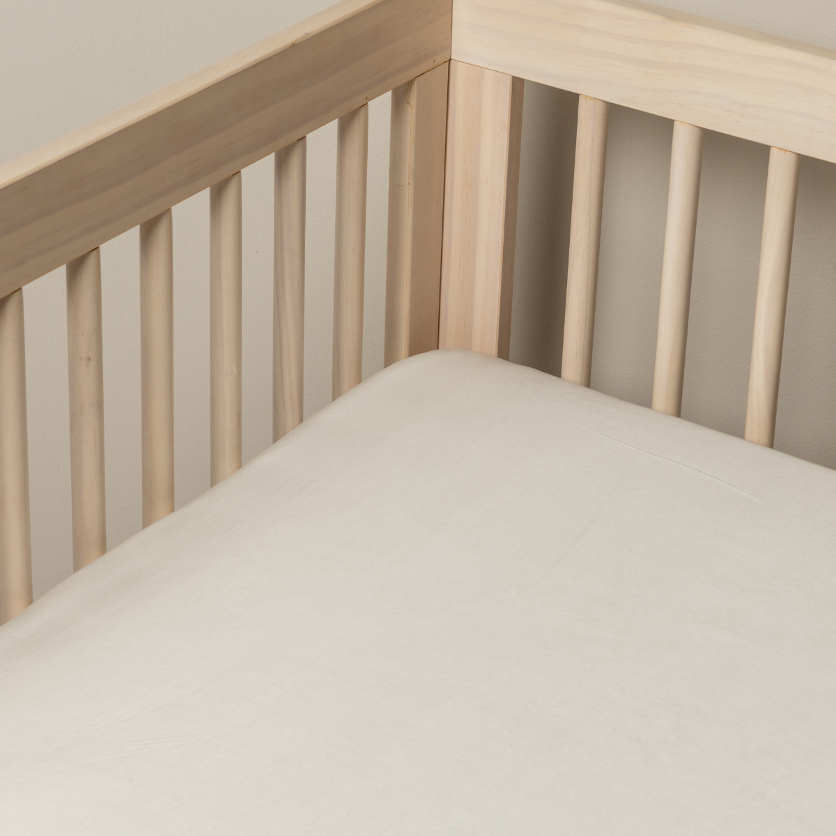 Madera Luxe crib sheet in Natural, fitted snugly in a light wood crib.