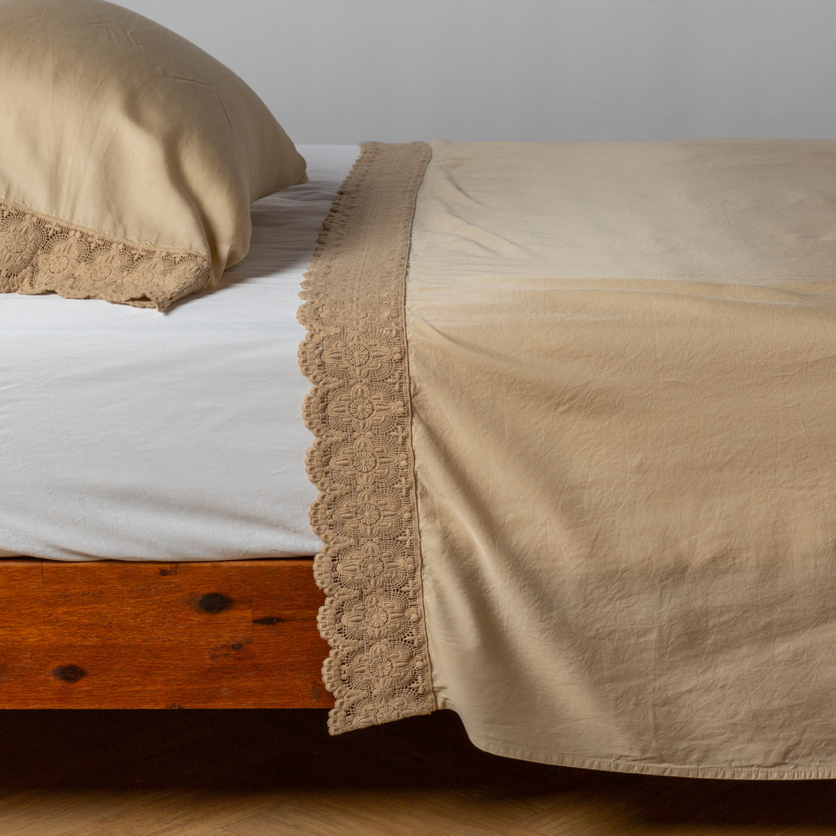 Honeycomb flat sheet and pillowcase with floral lace trim, draped on a wood-frame bed.