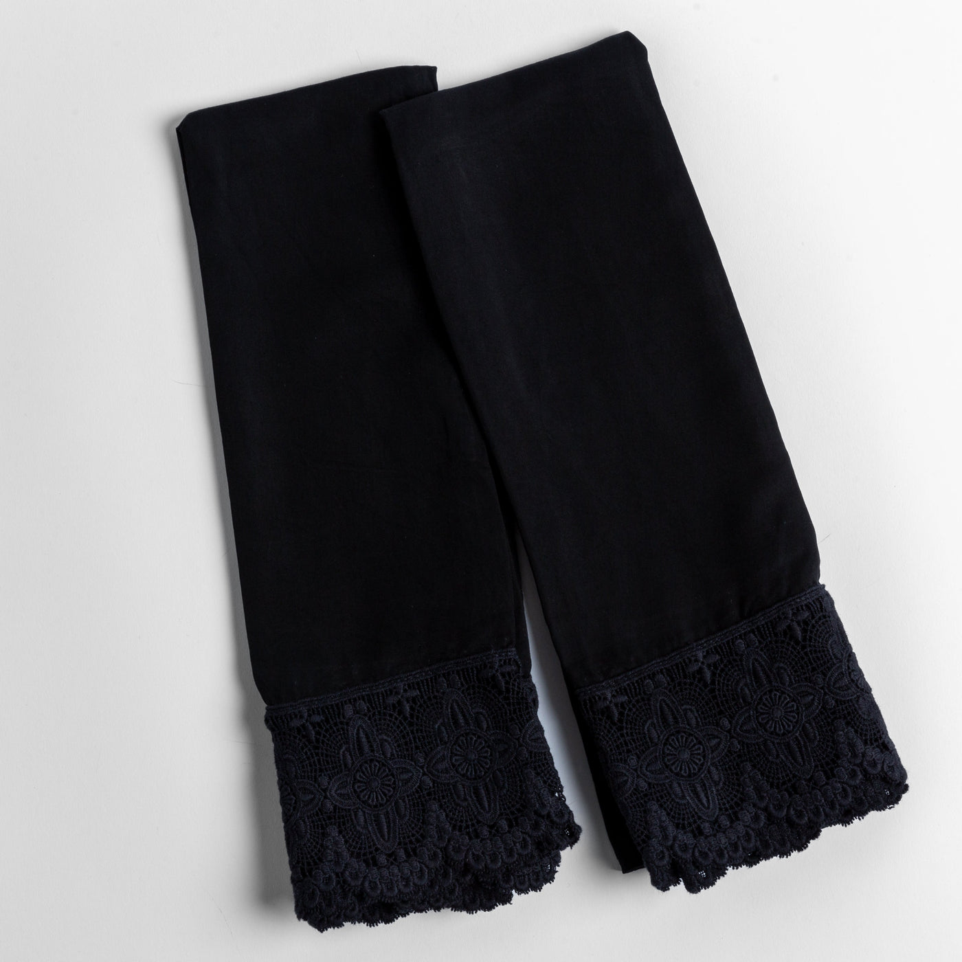 Corvino pillowcases with scalloped lace hem trim, folded flat to show border detail.