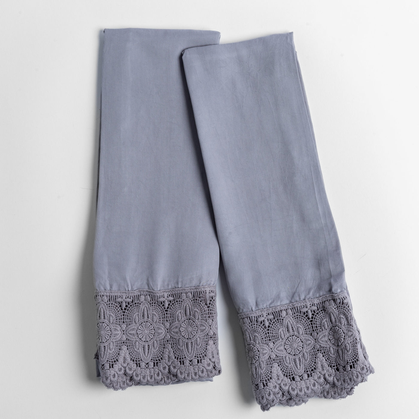 Pair of French Lavender pillowcases with wide floral lace trim hem, flat lay view.