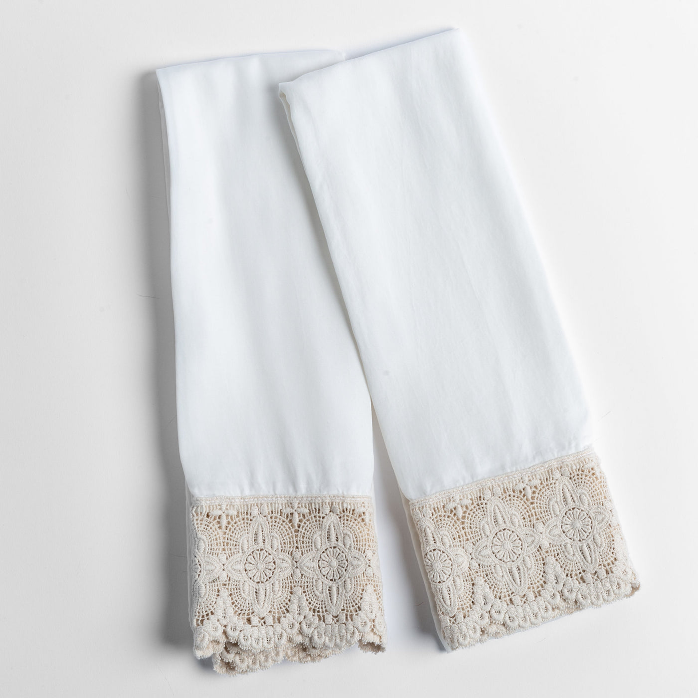 Winter White pillowcase pair with intricate taupe crochet lace trim, flat lay on white surface.