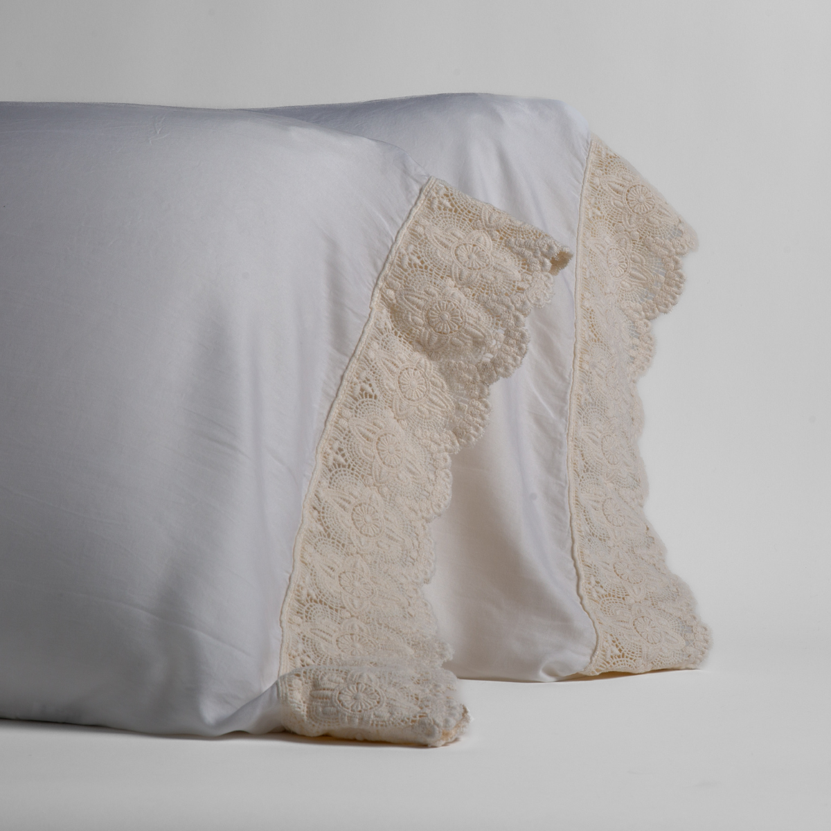 Close-up of Bella Notte Madera Luxe pillowcase pair showing scalloped lace trim detail.