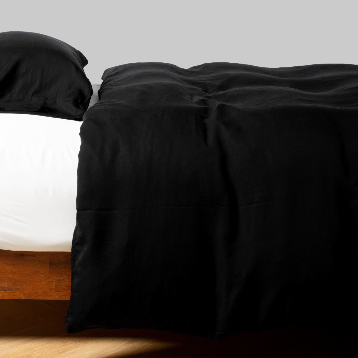 Corvino duvet cover draped over bed corner, showing deep black fabric with subtle sheen.