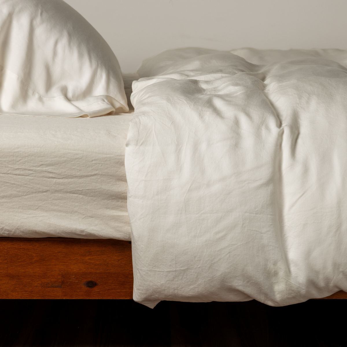 Bella Notte Madera Luxe duvet cover in Natural, casually draped on a wood-framed bed.