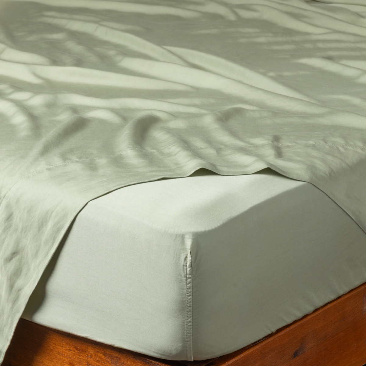 Fitted sheet corner detail showing snug mattress fit and smooth Desert Sage fabric drape.