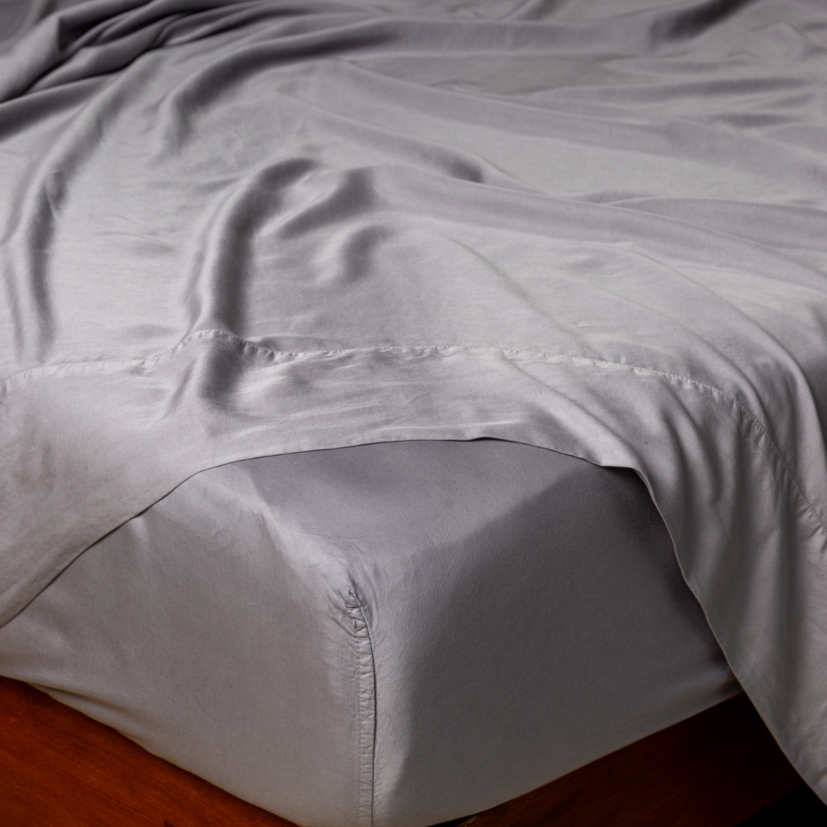 Close-up of French Lavender fitted sheet tucked onto mattress, silky drape visible.