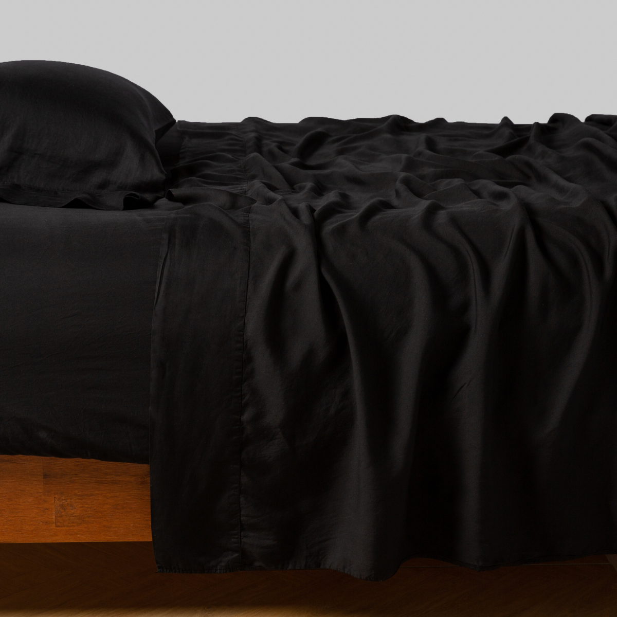 Flat sheet draped over bed in Corvino, showing satin hem detail and relaxed drape.