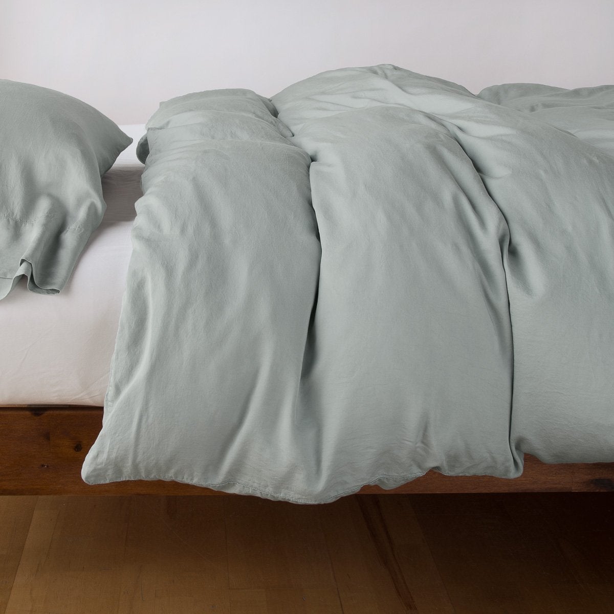 Eucalyptus duvet cover draped over a wood-frame bed, with matching pillowcases visible.