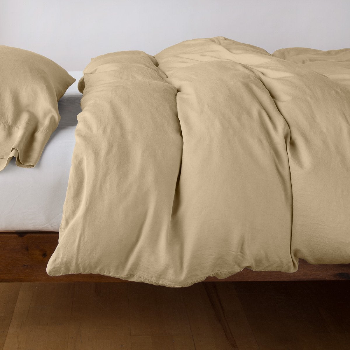 Honeycomb Madera Luxe duvet cover draped over bed with matching pillowcases, wood frame.