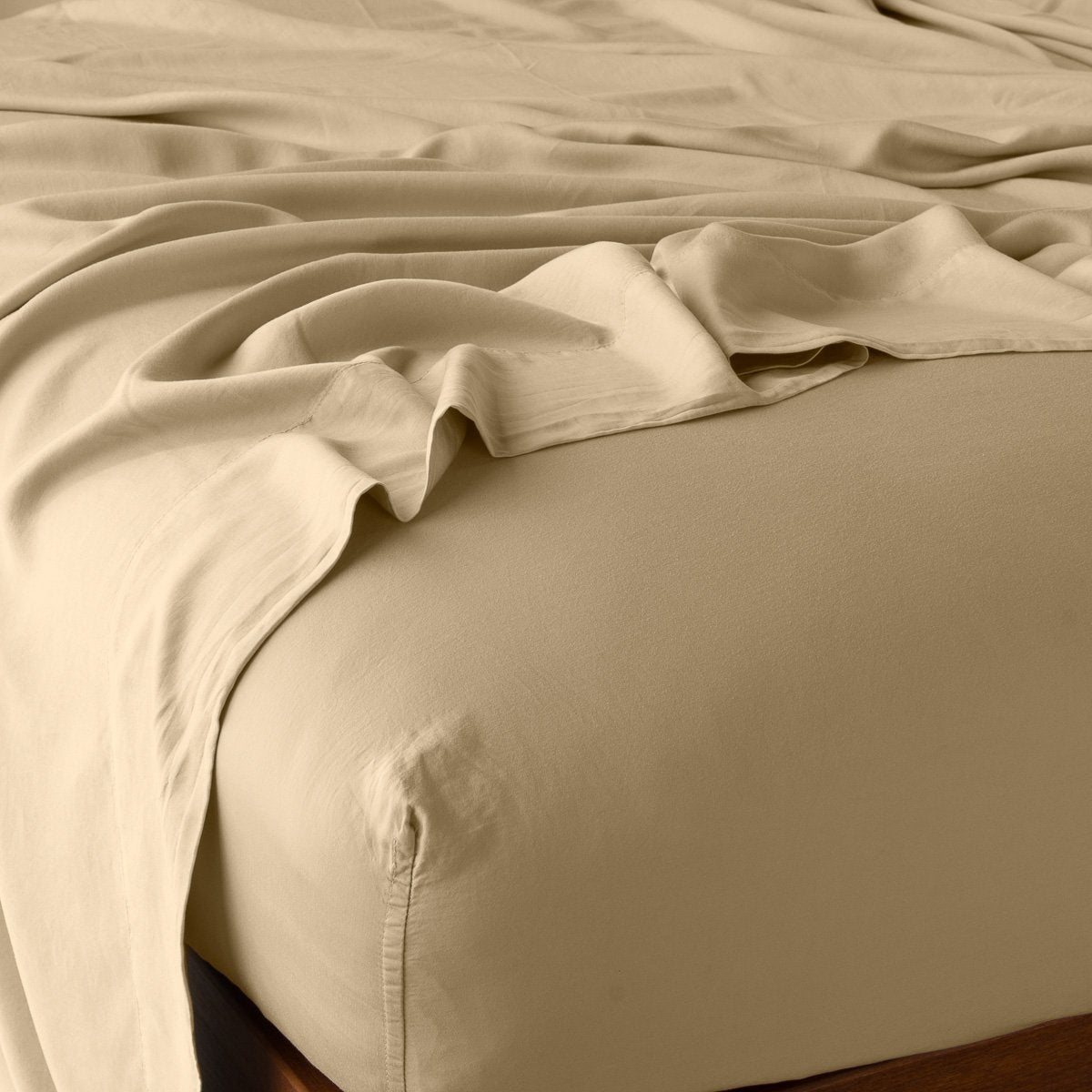 Honeycomb fitted sheet on bed with flat sheet draped softly over corner, warm gold tone.