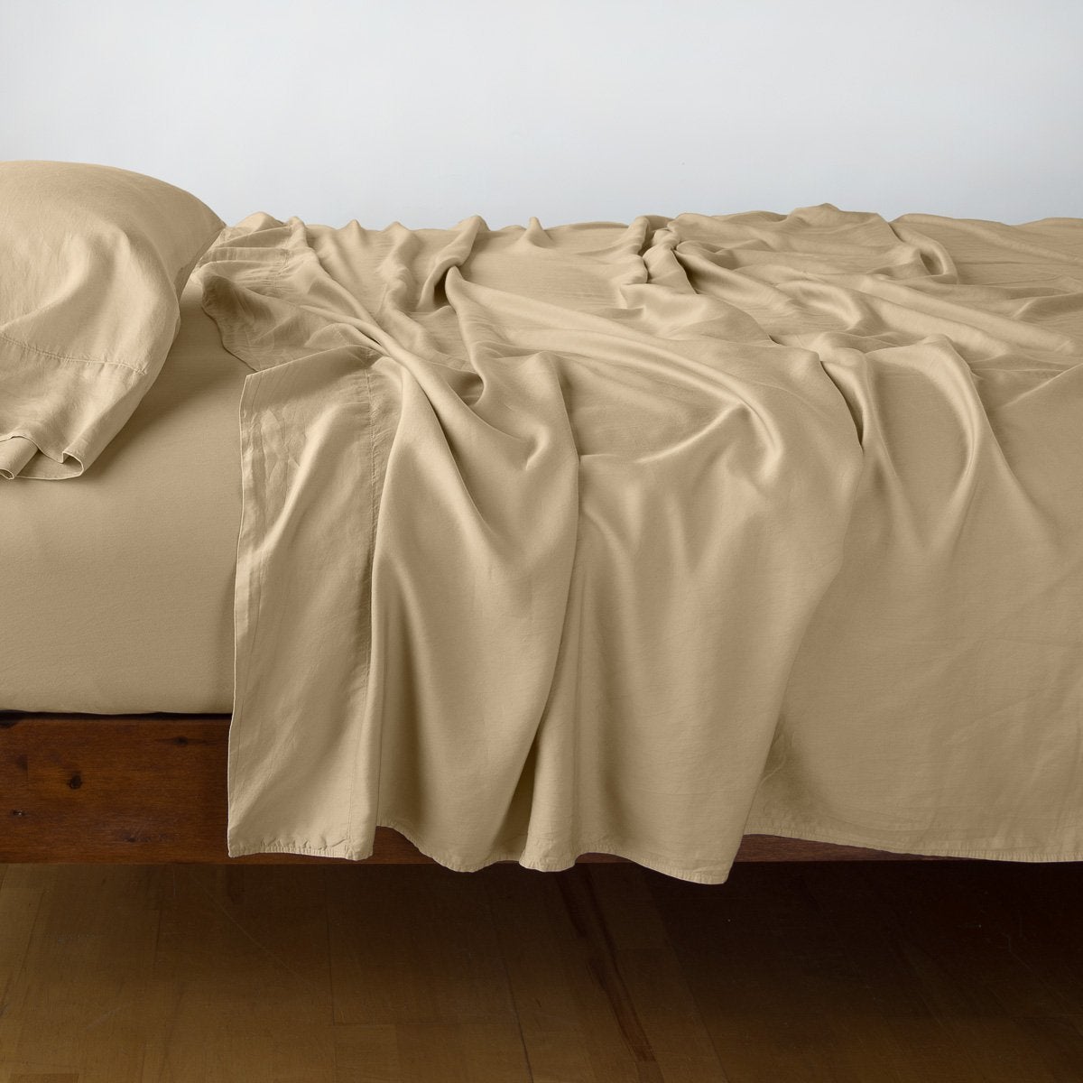 Honeycomb flat sheet draped loosely over a wood-frame bed, showing fluid fabric drape.