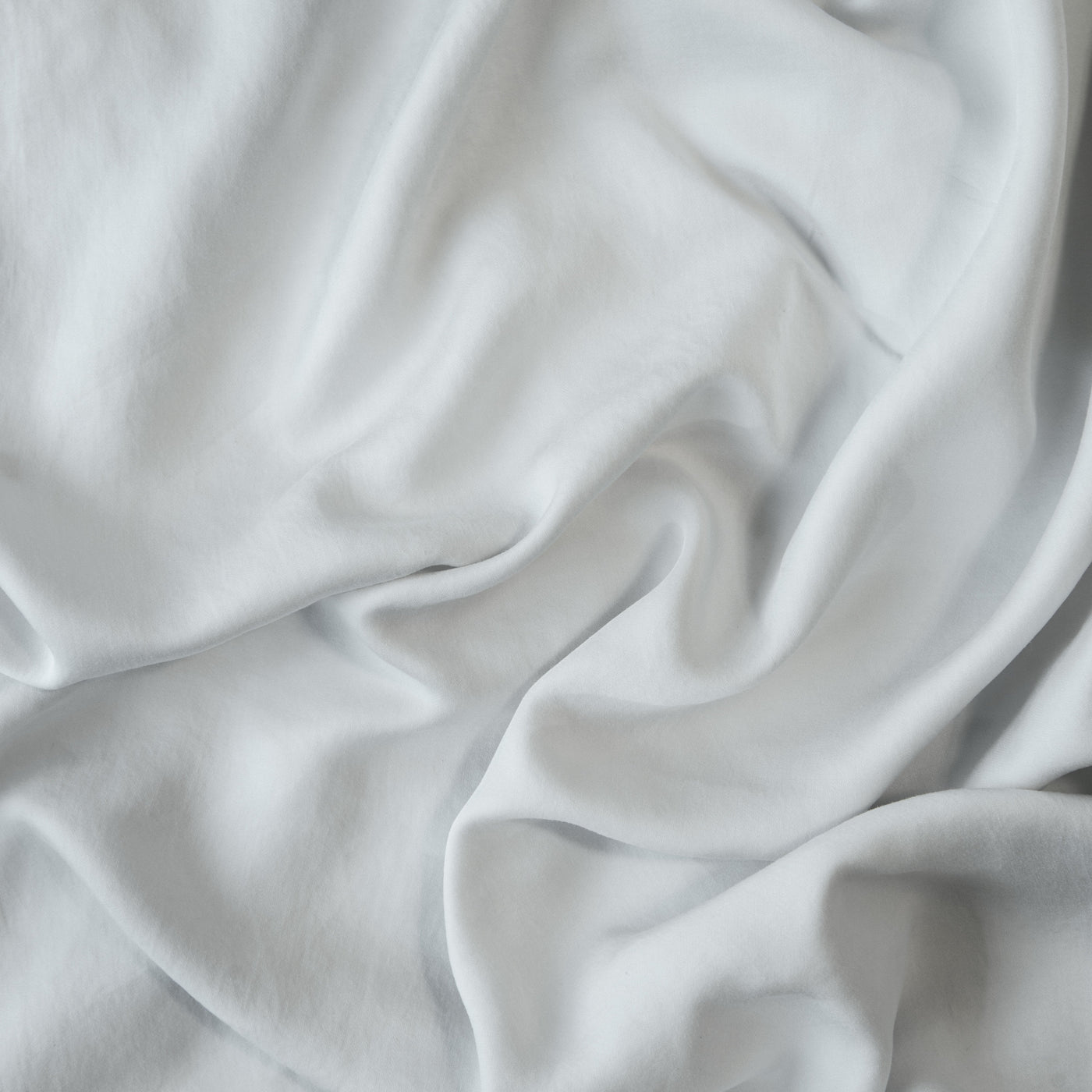 Soft Cloud Madera Luxe fabric draped in loose folds, showing silky texture and sheen.