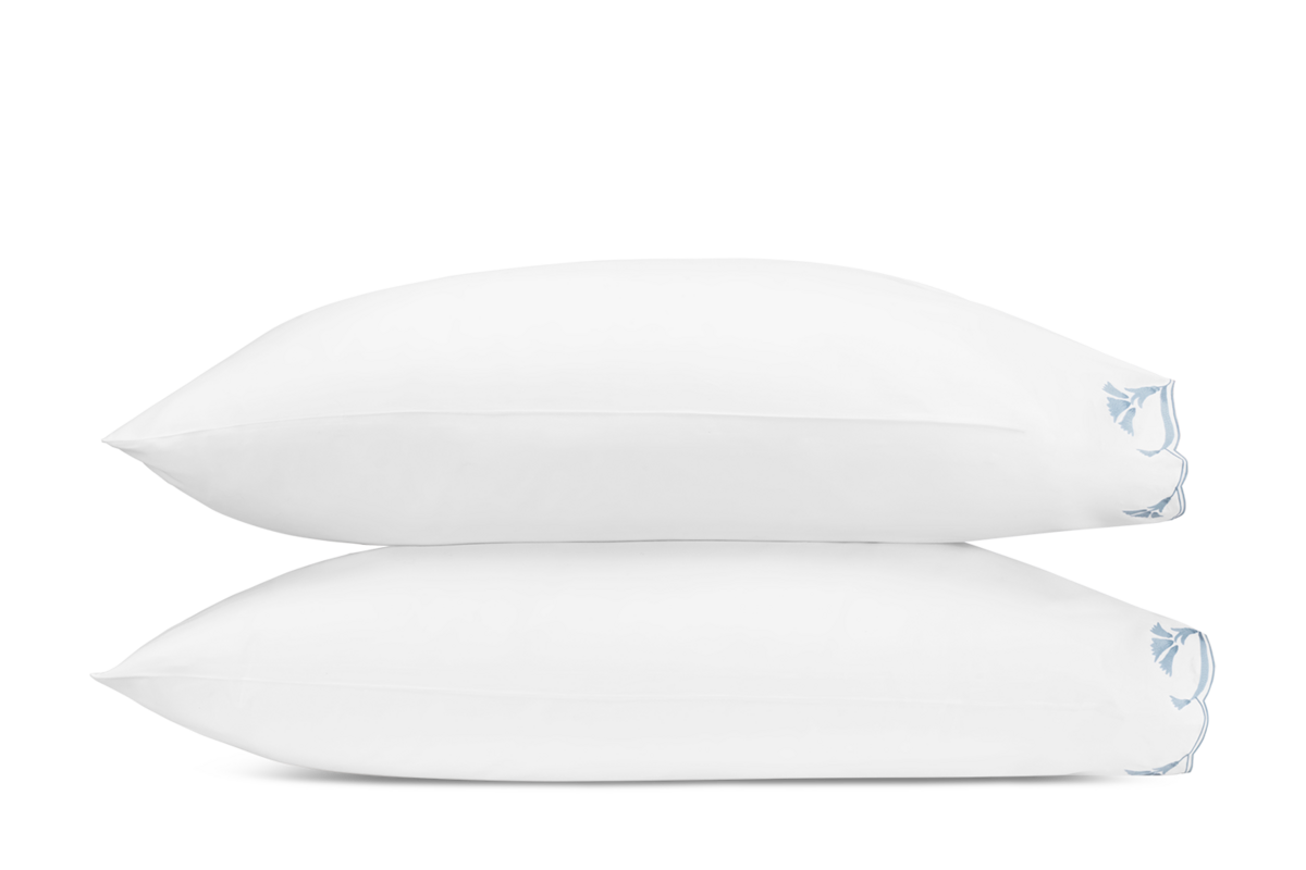 Side view of two stacked white Marcella pillowcases with pale blue embroidered trim detail.