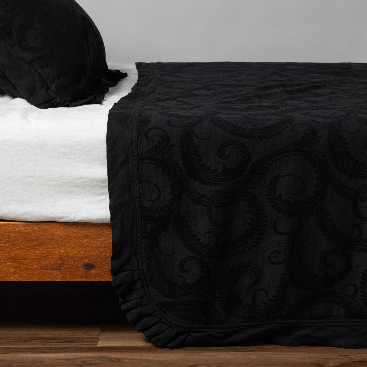Bella Notte Marisette bedspread in Corvino, showing ruffled hem detail on wood bed frame.