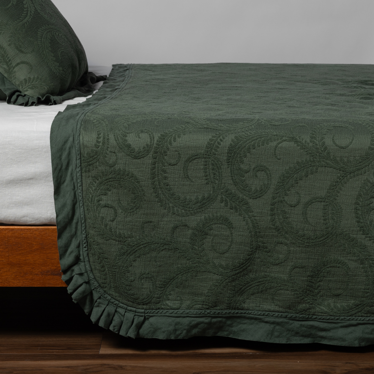 Juniper Marisette bedspread's ruffled hem and scrollwork quilting, styled on a bed corner.