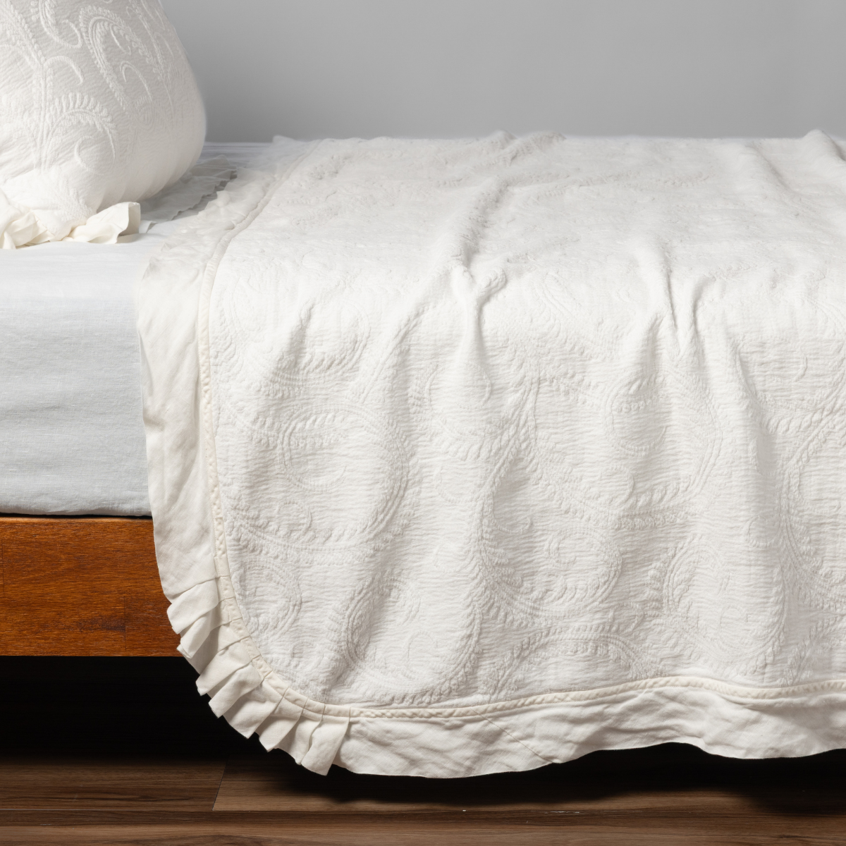 Bella Notte Marisette bedspread in Winter White, showing ruffled hem detail draped over bed foot.