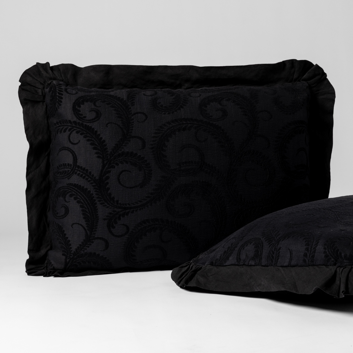 Corvino sham close-up showing tone-on-tone scroll embroidery and ruffled edge detail.