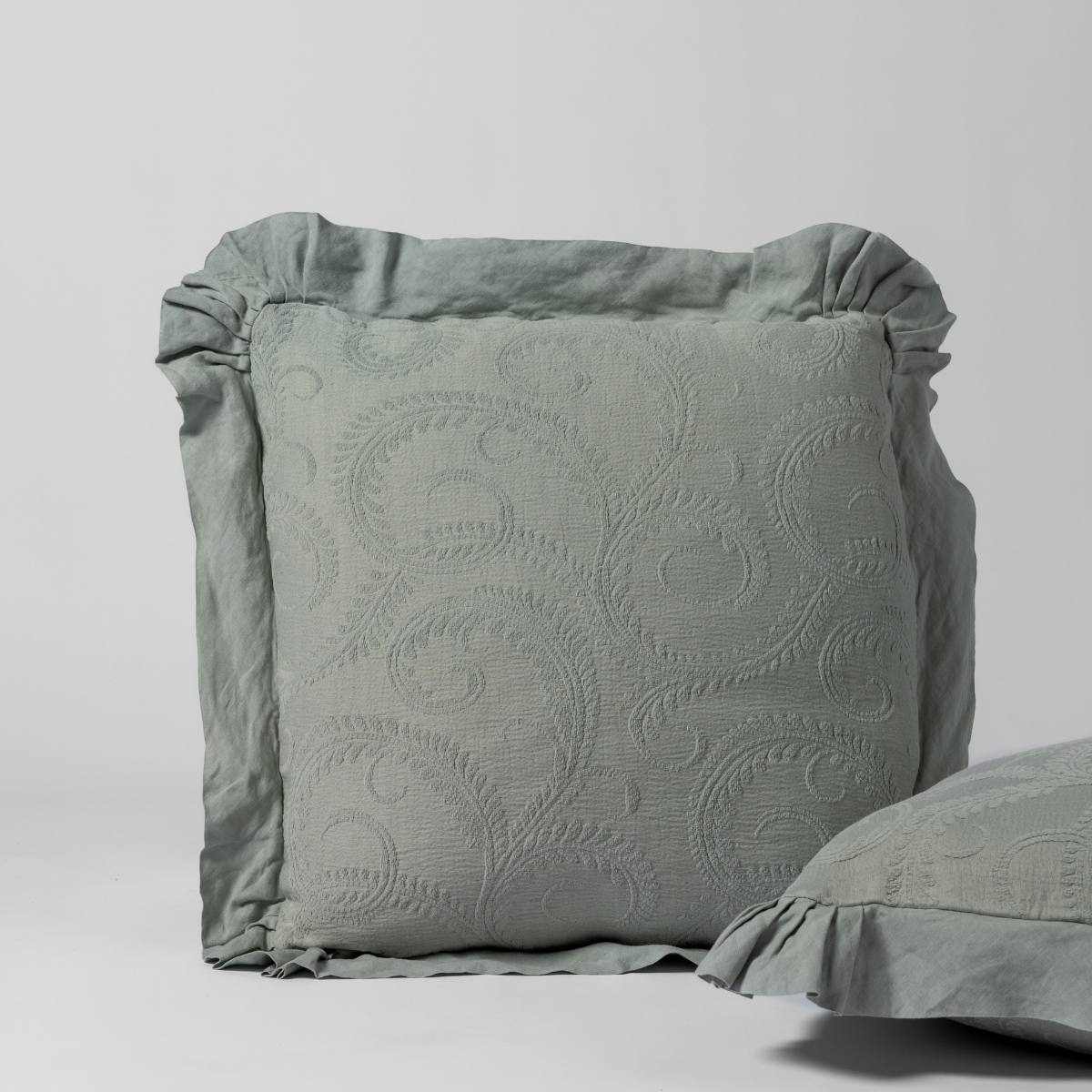 Close-up of Eucalyptus Marisette sham with scrolling matelassé pattern and ruffled linen border.