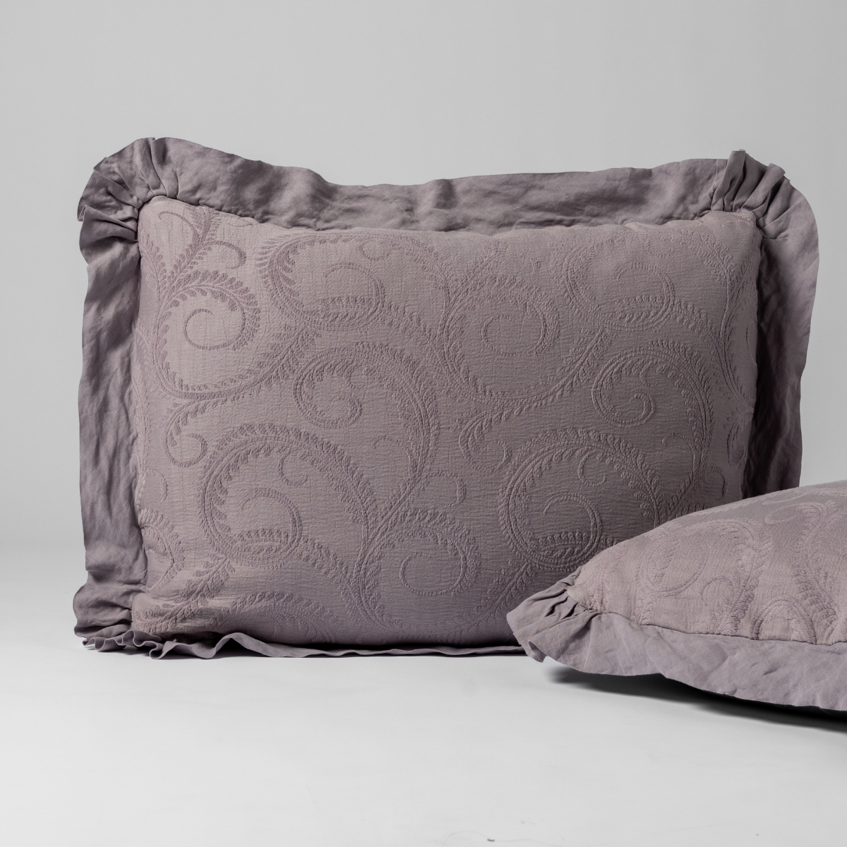 Close-up of Bella Notte Marisette sham in French Lavender with tone-on-tone scroll embroidery and ruffled edge.
