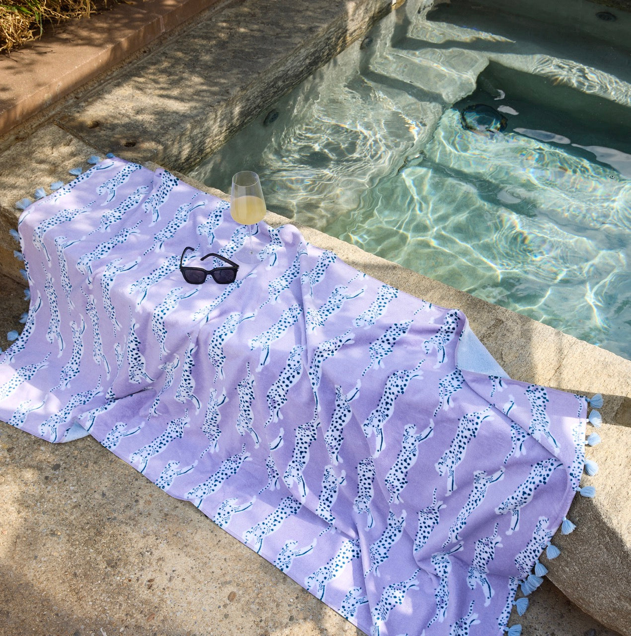 Image of Matouk Leaping Leopard Lilac Beach Towel by a pool