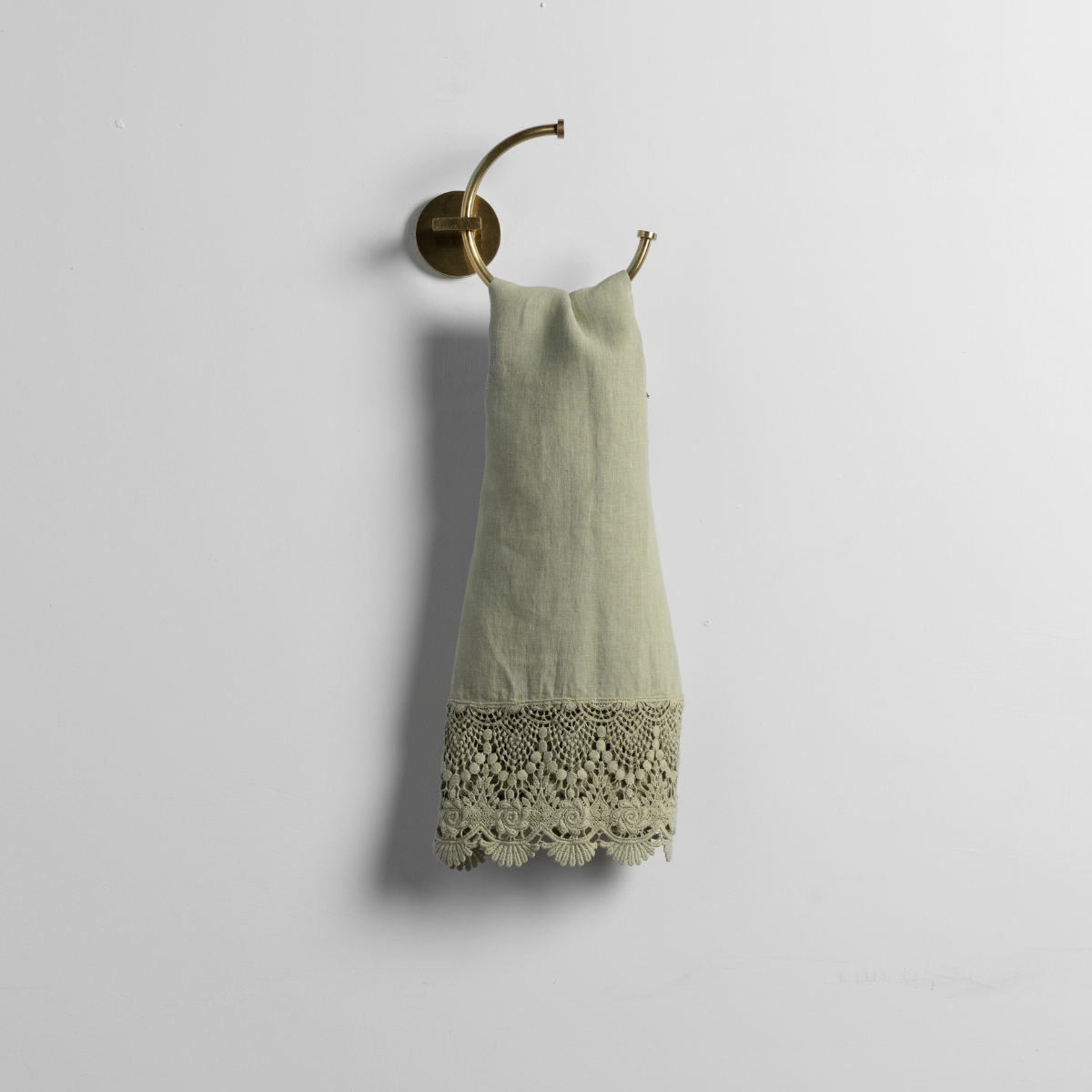 Desert Sage guest towel hung on brass ring hook, showing crochet lace hem detail.