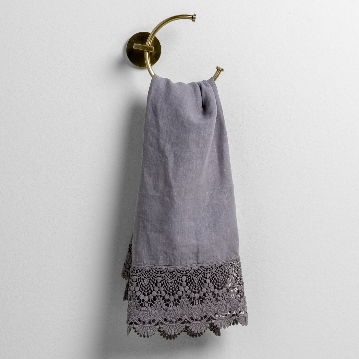 Bella Notte Mattine guest towel in French Lavender, draped on brass ring, intricate lace hem detail.