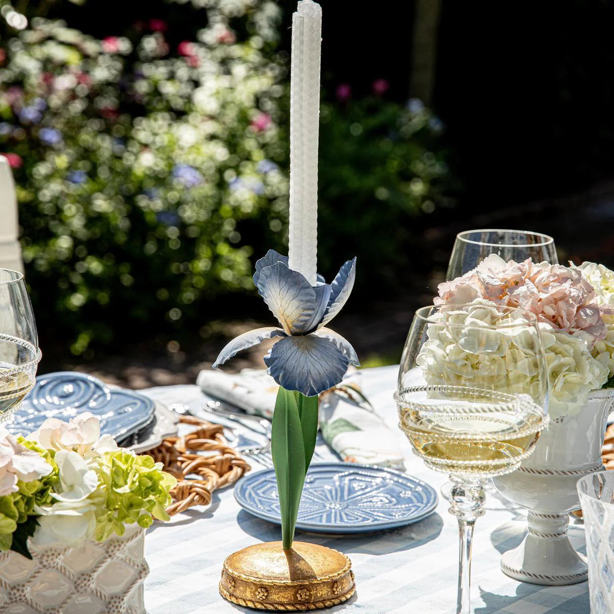 Blue iris candlestick holder with taper candle, styled on an outdoor garden tablescape.