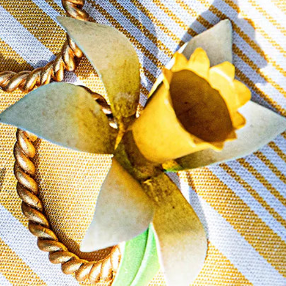 Close-up of Juliska Meadow Walk napkin ring with sunflower detail on gold-striped linen.