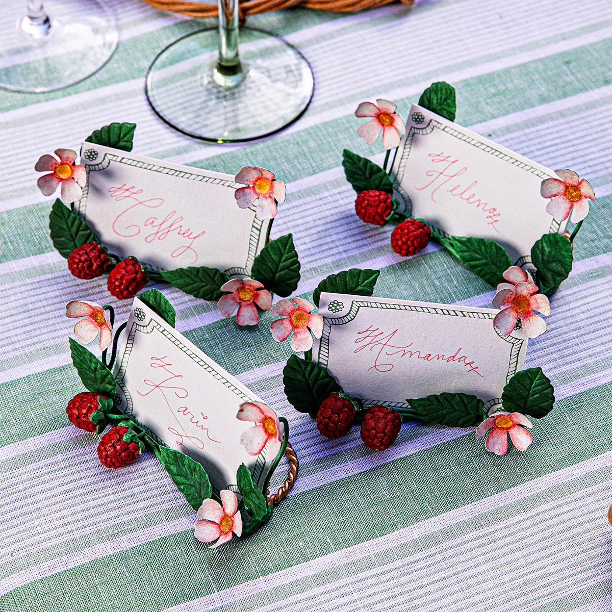 Juliska Berry place card holders with raspberry and pink flower motifs, displayed on striped linen.