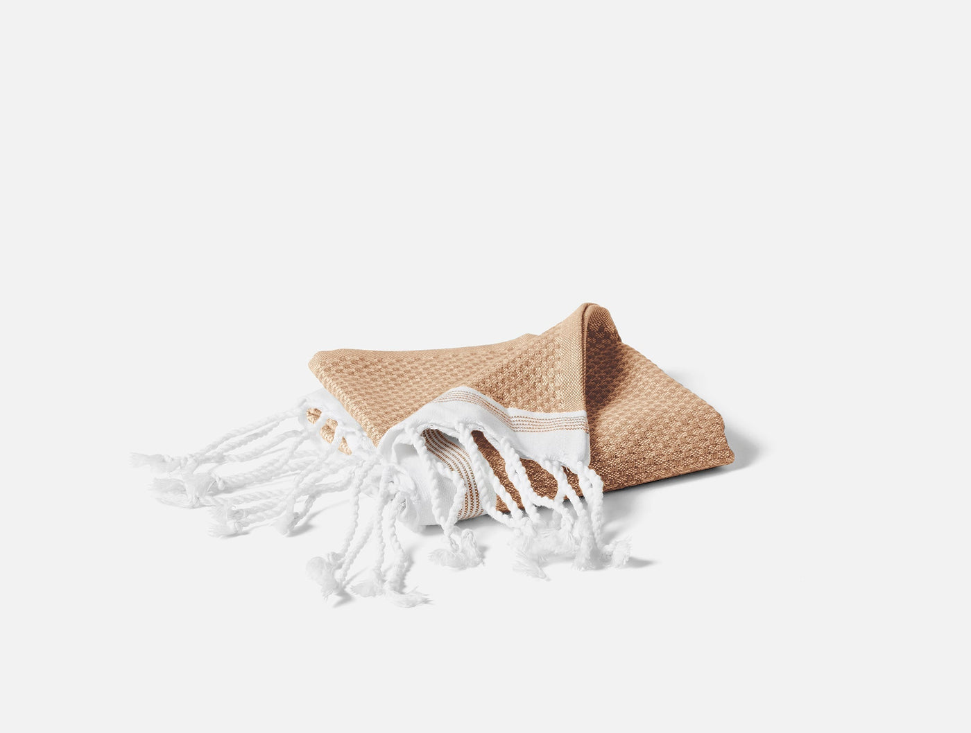 Coyuchi Mediterranean bath towel in caramel, folded with white fringe ends visible.