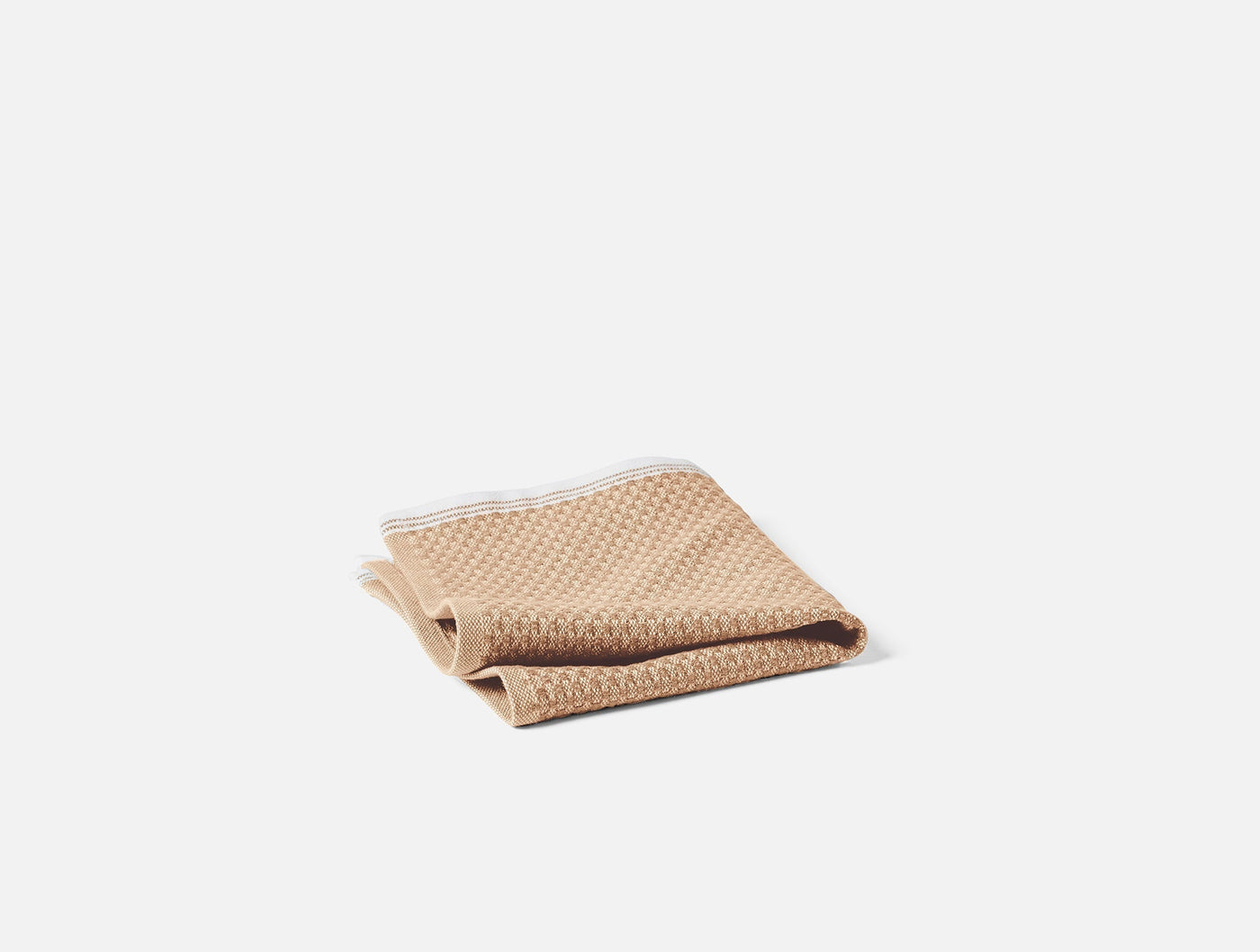 Coyuchi Mediterranean wash cloth folded, camel waffle weave with white trim detail.