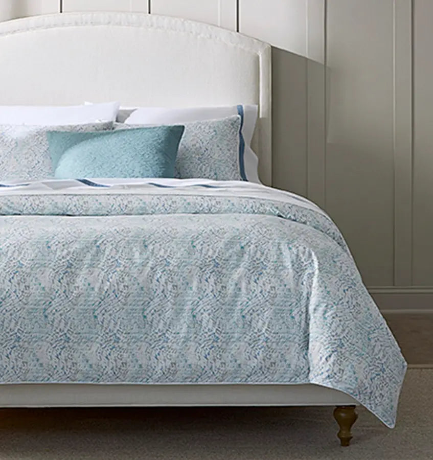 Bed styled with aqua patterned duvet and matching accent pillow against grey wall.
