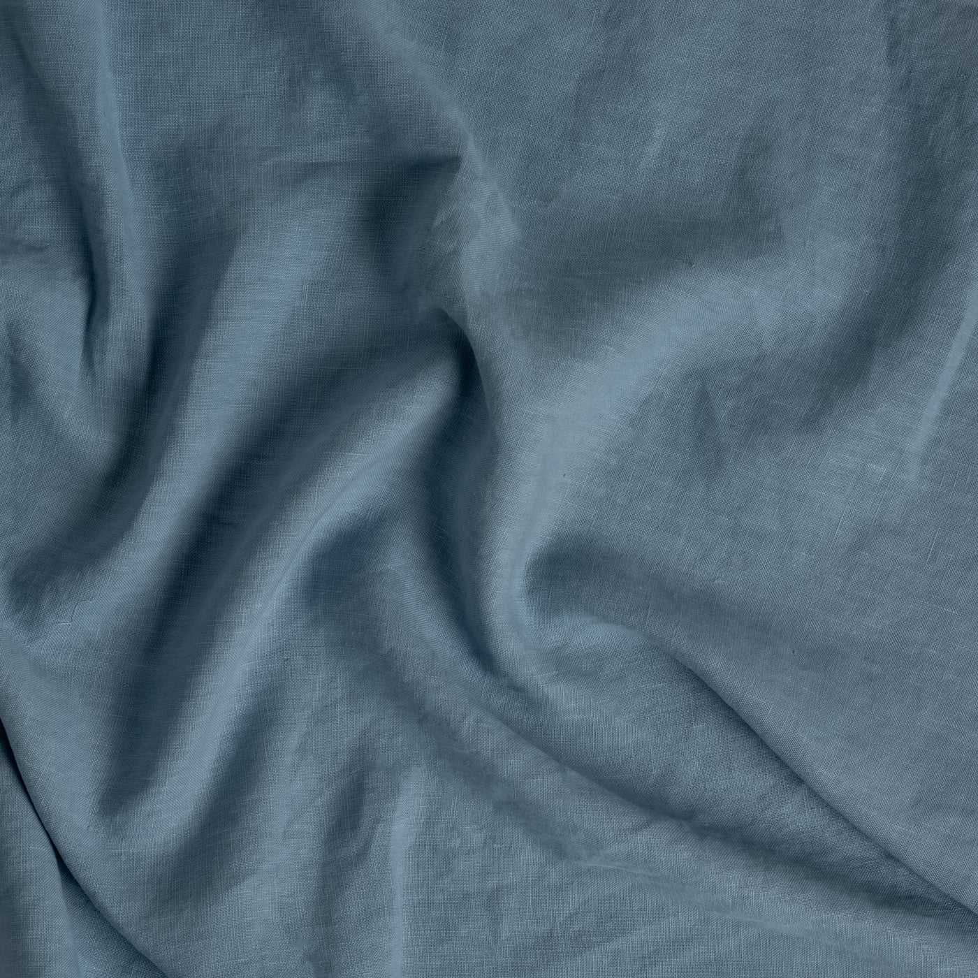 Bella Notte Austin bed skirt close-up showing draped Tahoe Blue linen fabric texture.