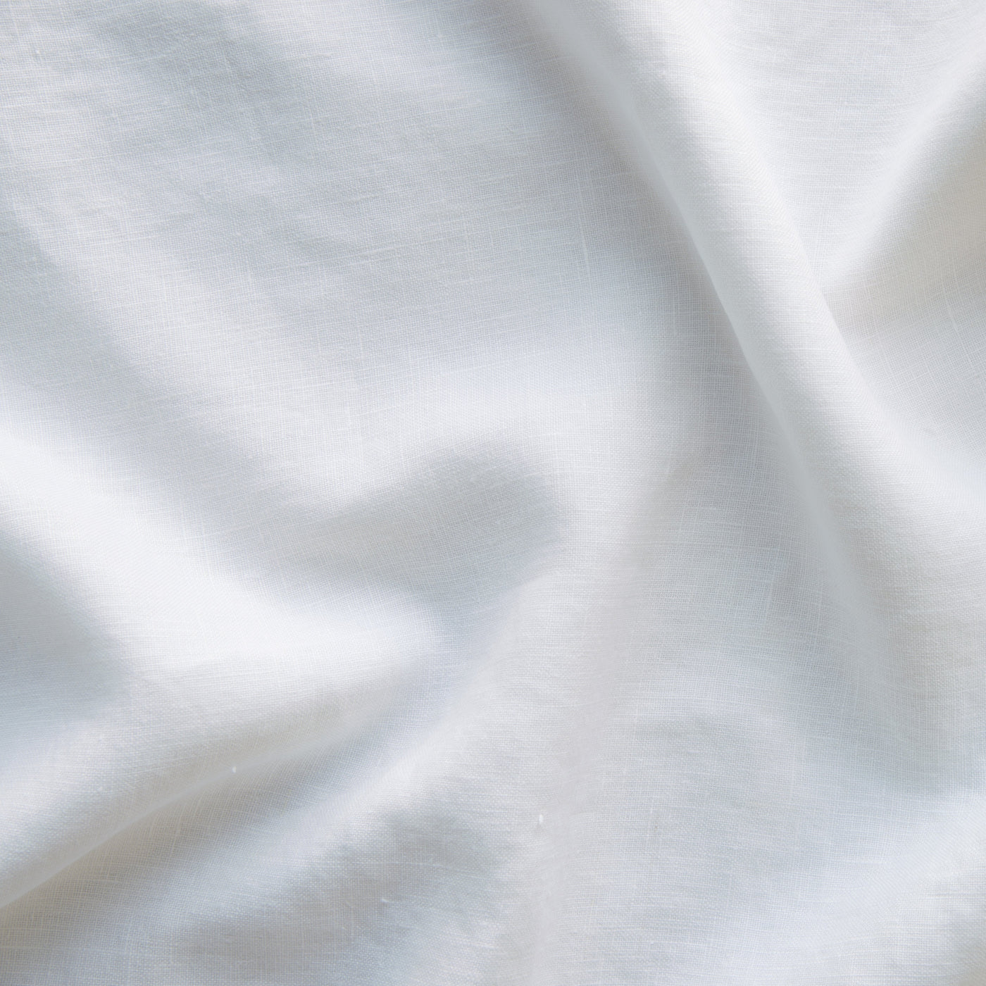 Close-up of draped White linen fabric showing soft folds and natural texture.